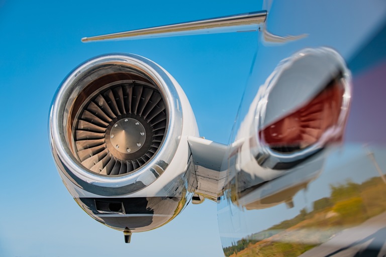 High mounted jet engine of a small business jet with a blue sky in the background