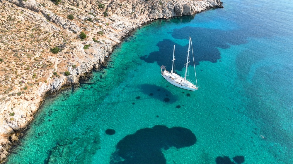 Aerial drone photo of luxury sail boat anchored in paradise bay of Ornos in island of Mykonos