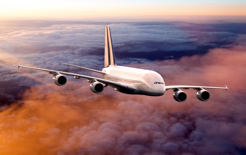 Airplane flies high in the sky over the sunset clouds