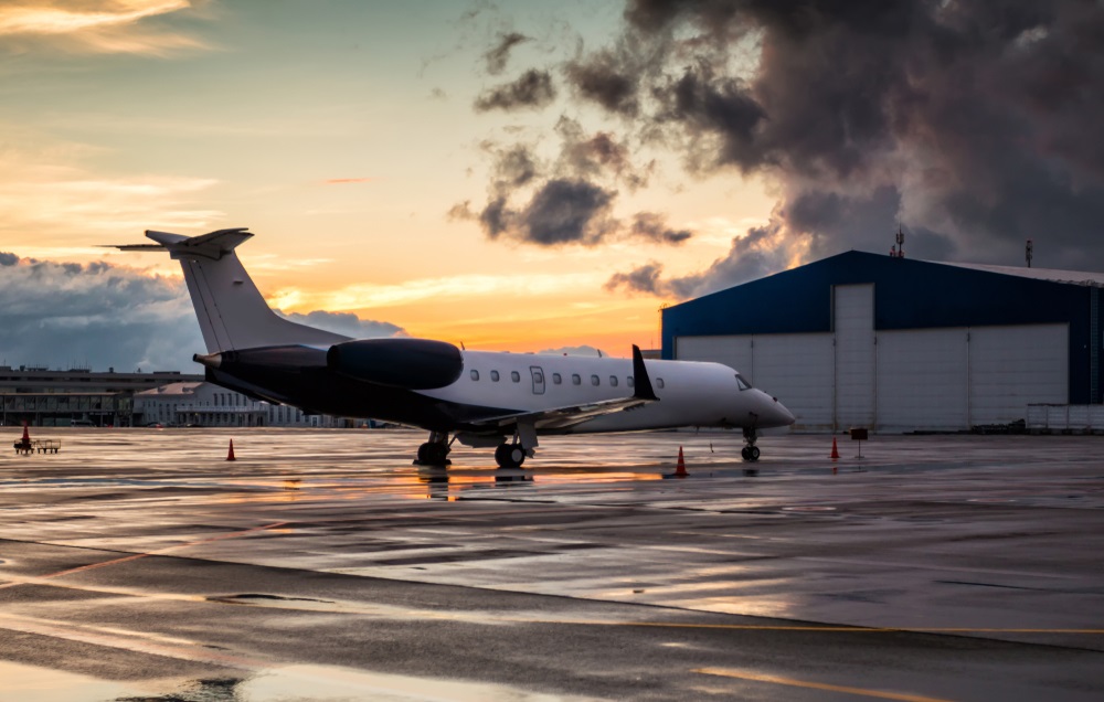 business jet at sunset after the rain on the airport apron near the hangar