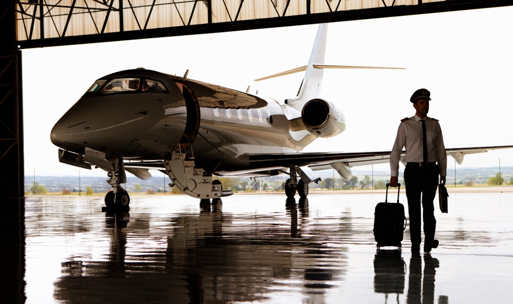 silhouette of pilot walking away from private jet in hangar