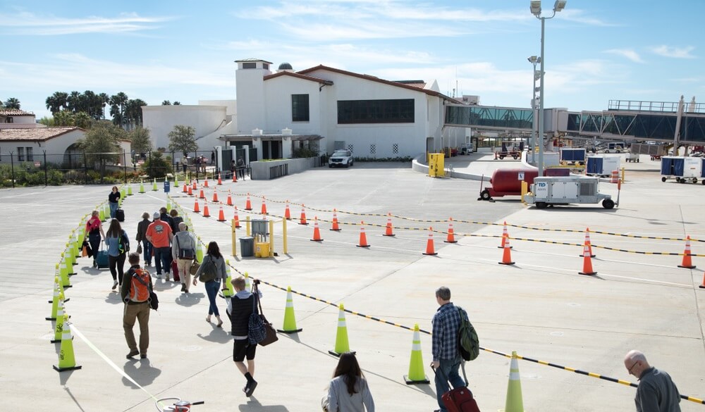 Airplane passengers walking across the airfield tarmac to the airport arrivals terminal at Santa Barbara Municipal (SBA)