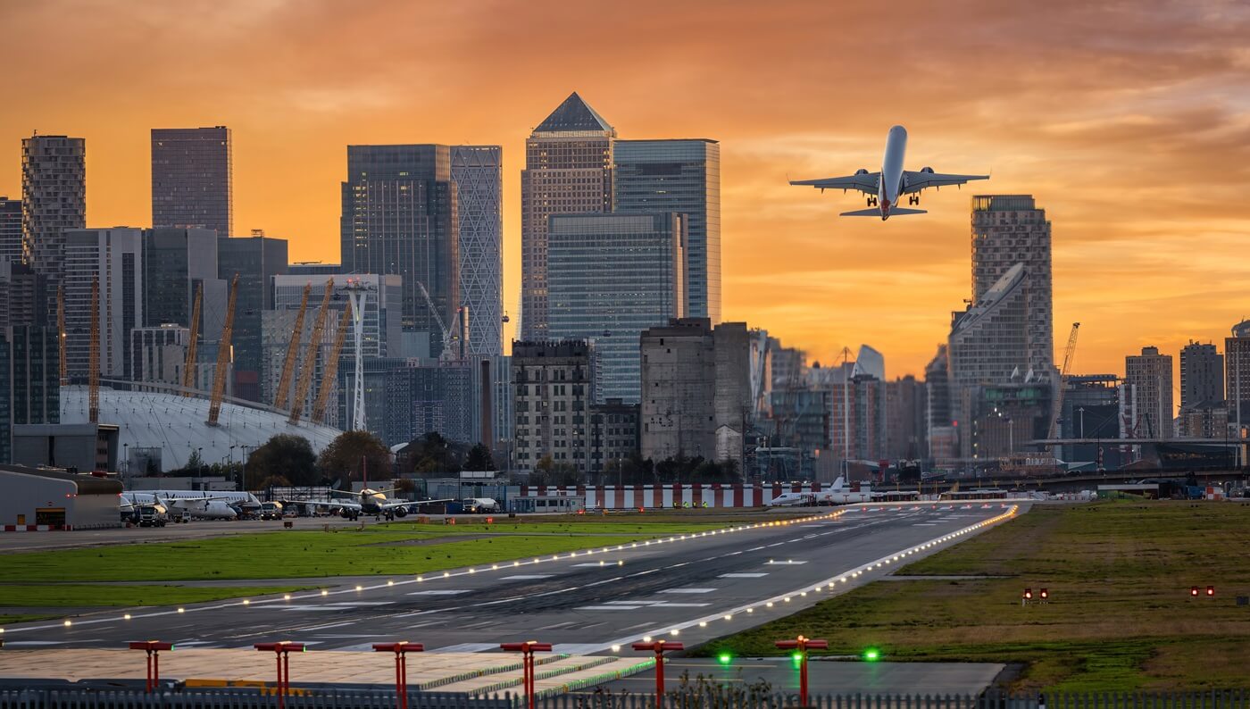 London skyline with Canary Wharf district and the runway of the City Airport in front during sunset time 