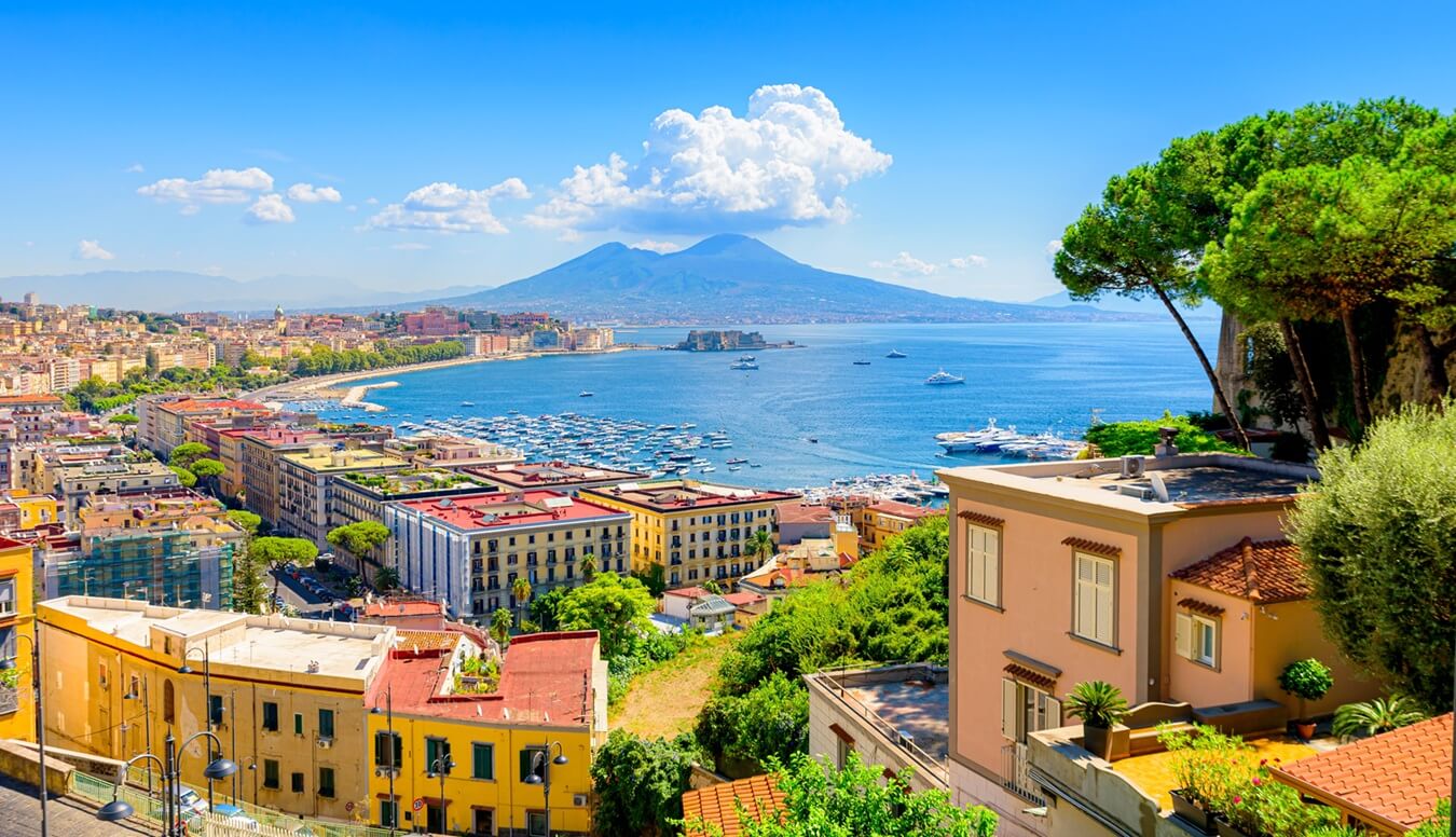 View of the Gulf of Naples from the Posillipo hill with Mount Vesuvius far in the background and some pine trees in foreground