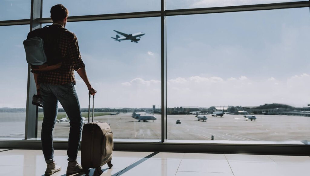 man is watching plane flying from airport