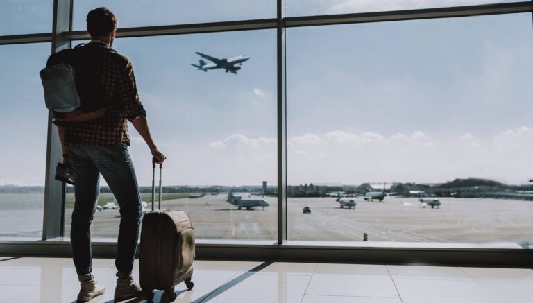 man is watching plane flying from airport