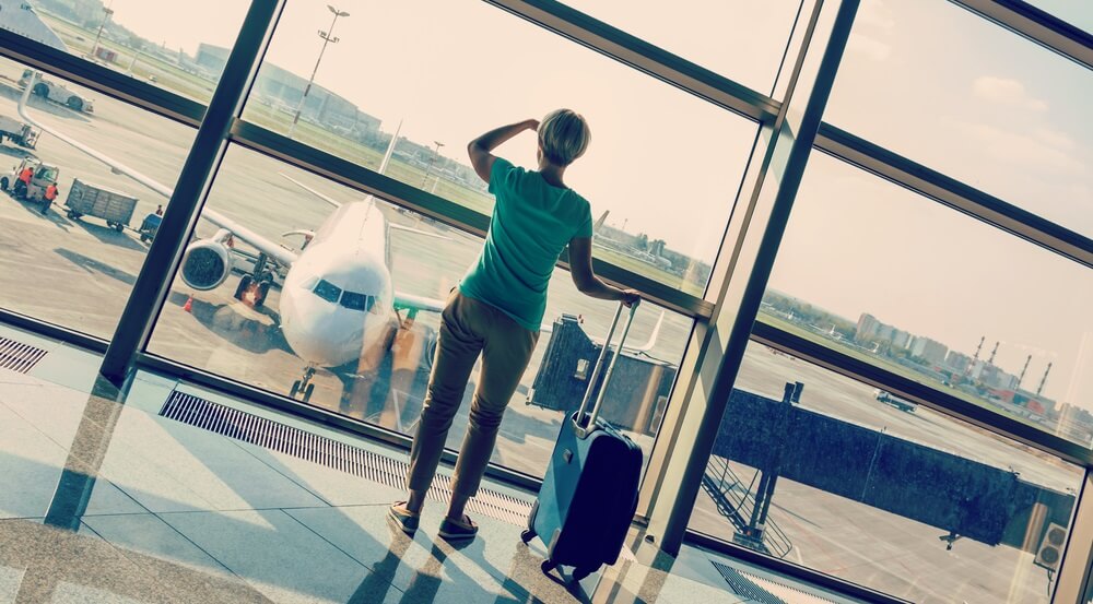 beautiful young woman with blond short hair with a suitcase at the airport and waiting for her flight