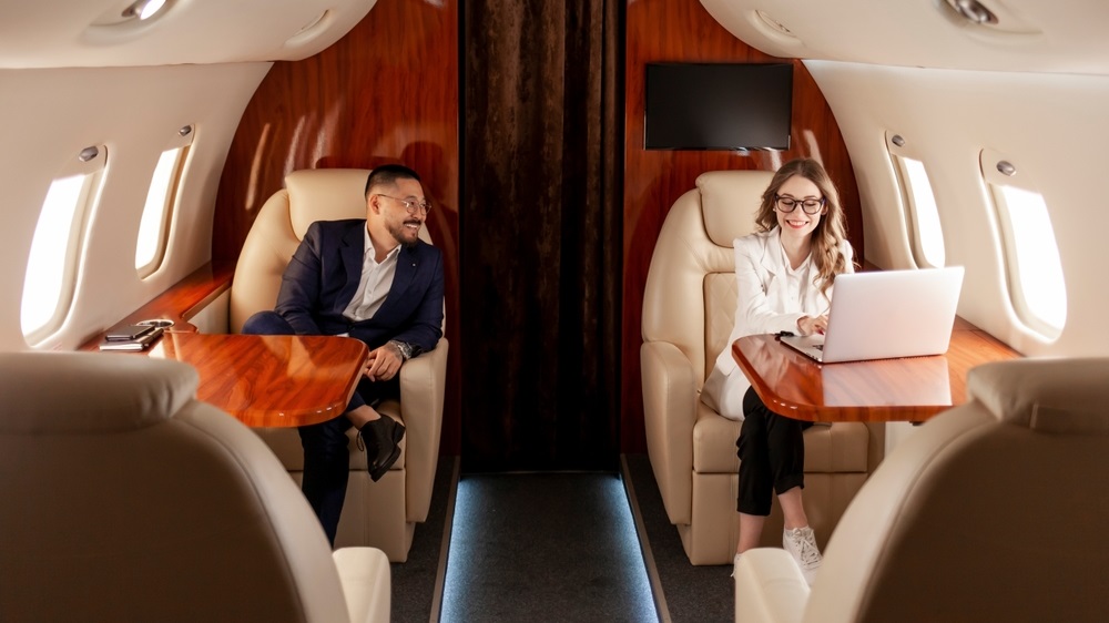 business people are flying in private luxury plane, asian businessman in suit and woman manager are sitting in the plane and discussing the workflow