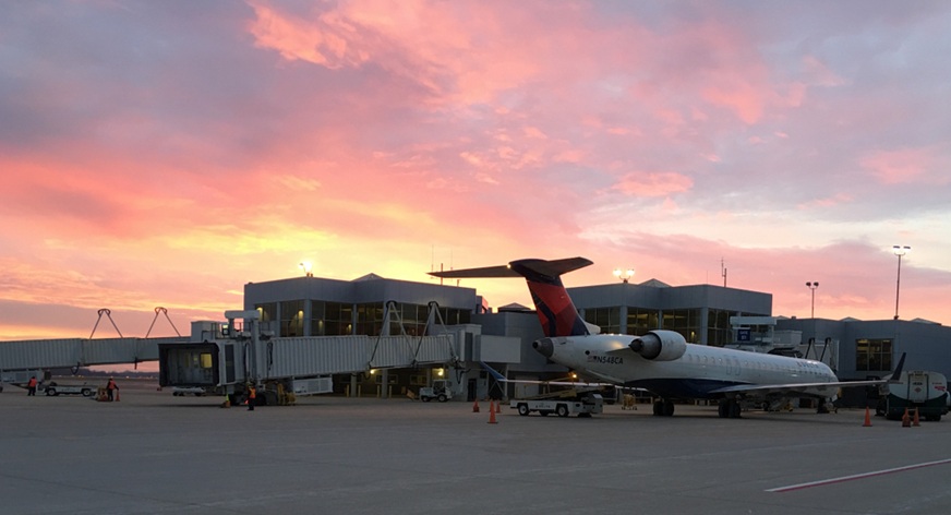 Delta Airlines jet parked at the terminal of Austin Straubel International Airport at sunset