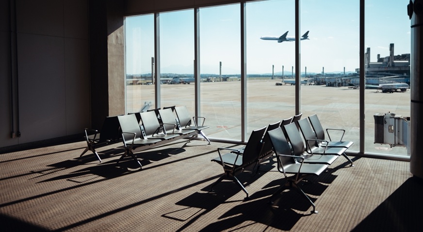 airport terminal seating area with a large window view of the runway and an airplane taking off