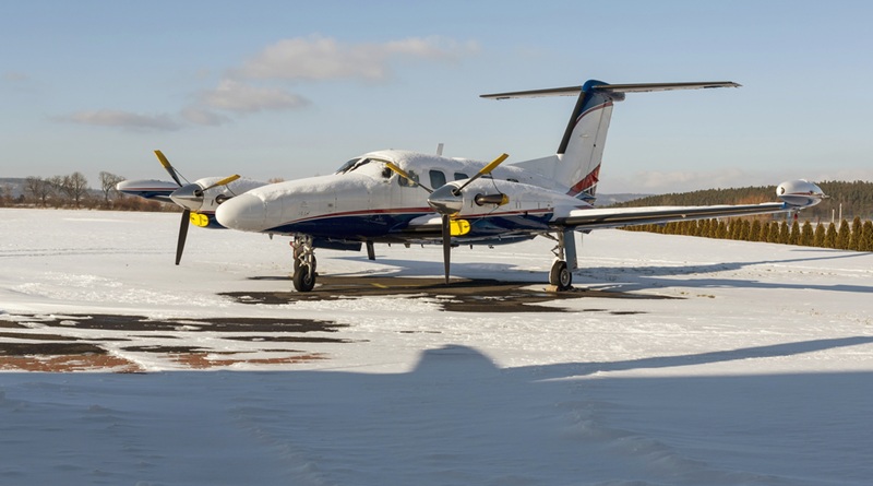 Twin-engine-aircraft-with-turboprop-power-plant-on-runway-under-snow-in-sunny-winter-day