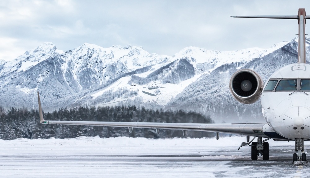 Front view of the luxury private jet on the winter airport apron on the background of high picturesque mountains