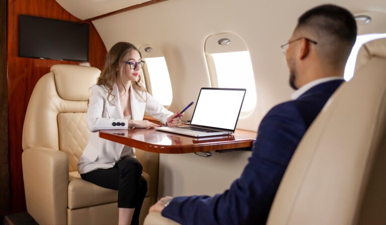 businesswoman in suit is talking to business partner and pointing at blank laptop screen